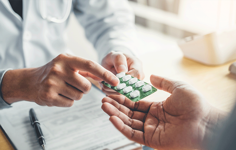 Pharmacist pointing to tablets and handing them to a customer